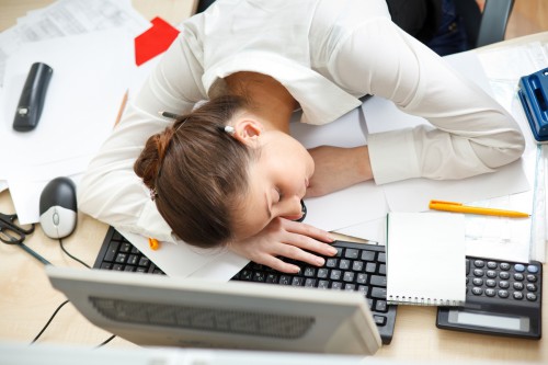 Office life. Young woman sleeping at workplace.